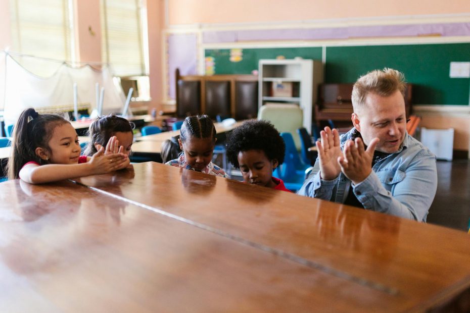 kids standing beside man sitting at the piano and clapping hands